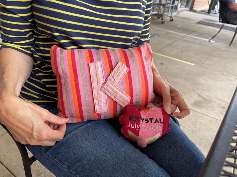 A woman holding a zipper pouch made from a Victoria's Secret bag