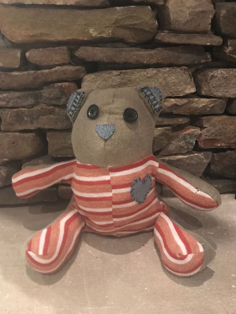 A handmade memory bear sewn from a loved one's striped shirt, with a stitched denim heart